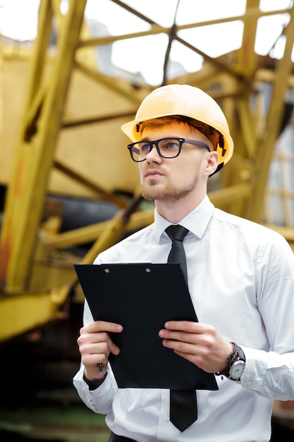 Engineer builder in a helmet holds folder at the construction site