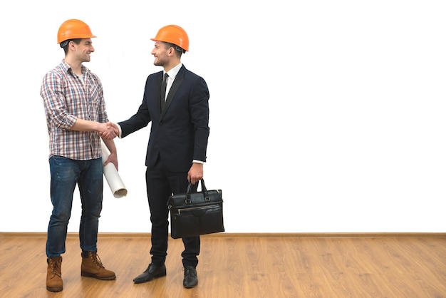 The engineer and a businessman handshake on the white wall background