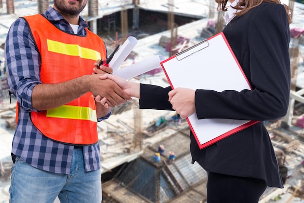 Engineer and businesswoman shaking hand after complete accept Price agreementBuilding construction contract worth several billion