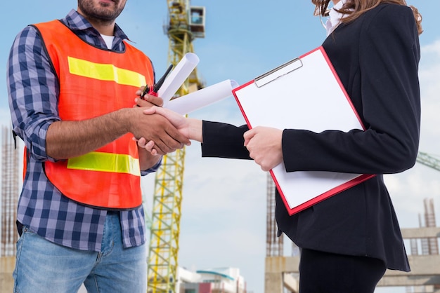 Engineer and businesswoman shaking hand after complete accept Price agreementBuilding construction contract worth several billion