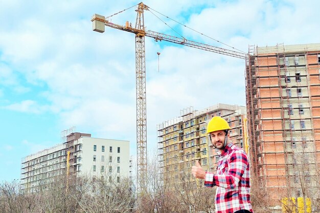 Инженер проверяет строительство незавершенного здания и показывает большой палец на конце
