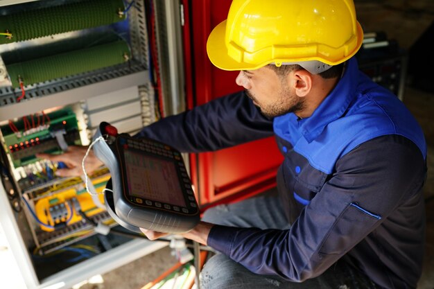 Engineer checking control panel and teaching new automatics\
robot arm and operating control machine in factory