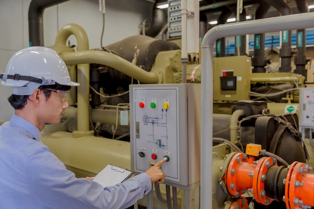 Hvacシステムの高温状態を作り出すための稼働中の産業用チラー、温水ポンプ、およびパイプラインをチェックするエンジニア。