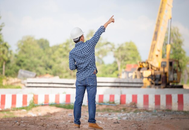 Фото Инженер проверяет проект на строительной площадке начальник в твердой шляпе на строительной площадке инфраструктуры