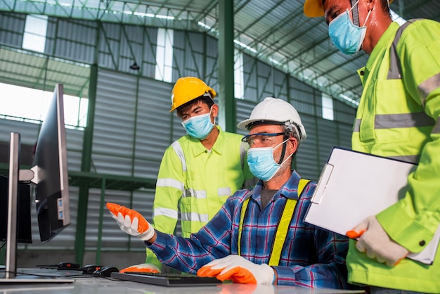 Engineer and construction workers wearing safety helmets and face masks