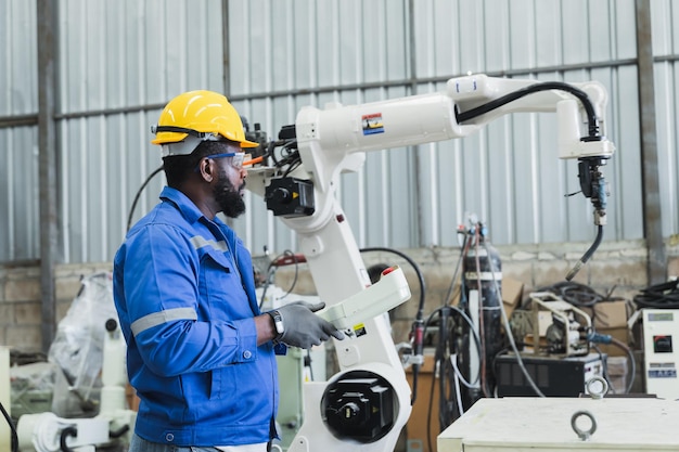 engineer controlling robot arm at factory checking the operation of robot arm