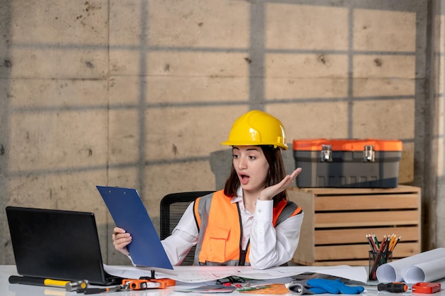 Foto ingegnere carino giovane ragazza bruna intelligente lavoratore civile in casco e giubbotto scioccato