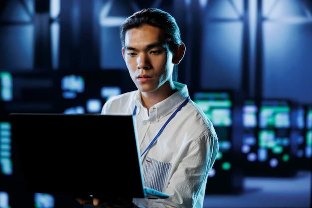 Photo engineer in data center with laptop