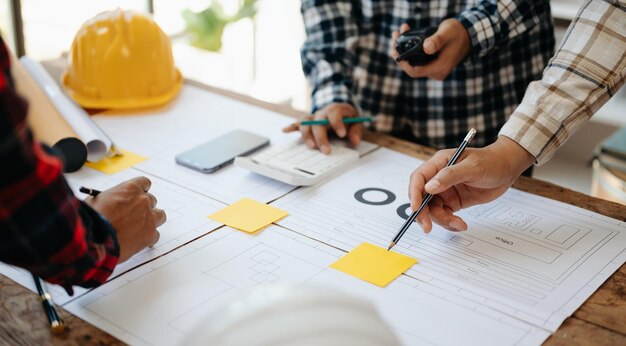 Engineer desk with object paper and tablet with blurry engineer teamwork hardworking to consults about their building project in office