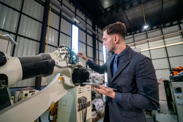Engineer Examining Robotic Arm in Industrial Facility During Daytime