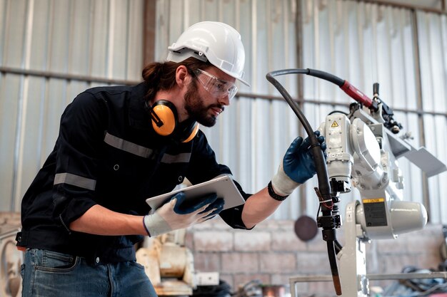 Engineer factory industry wearing safety uniform work and checking system of the welding robots for welding steel electrical by control system robot automate for industry manufacture concept