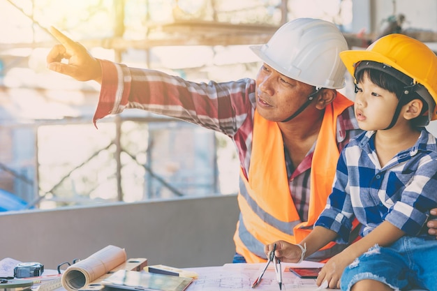 Ingegnere padre e figlio che giocano insieme caposquadra che insegna ragazzo costruttore al cantiere