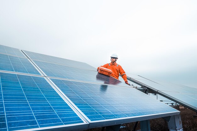 Engineer fixing solar panel against sky