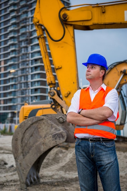 Foto ingegnere davanti all'escavatore in un cantiere.