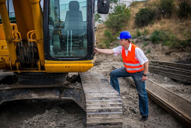 Photo engineer in front of excavator on a construction site