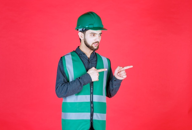 Engineer in green uniform and helmet showing the right side. 