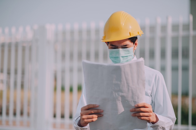 Engineer holding blue print construction site  background