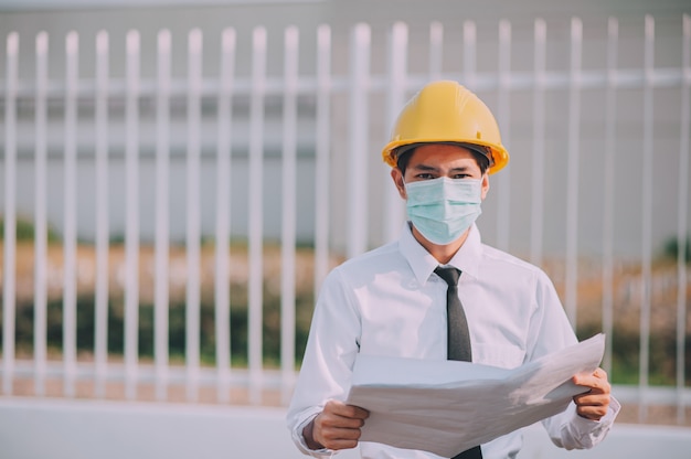 Engineer holding blue print construction site  background