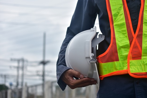 Foto ingegnere che tiene la sicurezza dell'elmetto sul posto di lavoro e appaltatore di architettura pesante dello sviluppo edilizio di costruzione, caposquadra tecnico di occupazione dell'elettricista, sicurezza dell'elmetto protettivo per uso professionale del supervisore