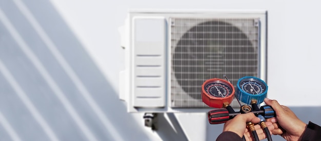 Photo engineer holding pressure gauge checking air conditioner operation