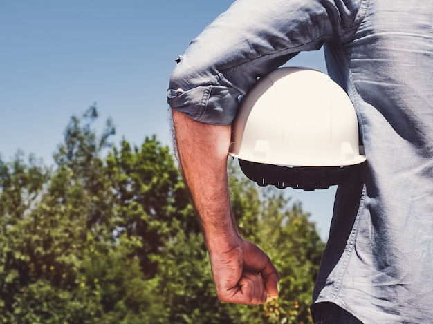 Engineer, holding white hardhat in the park