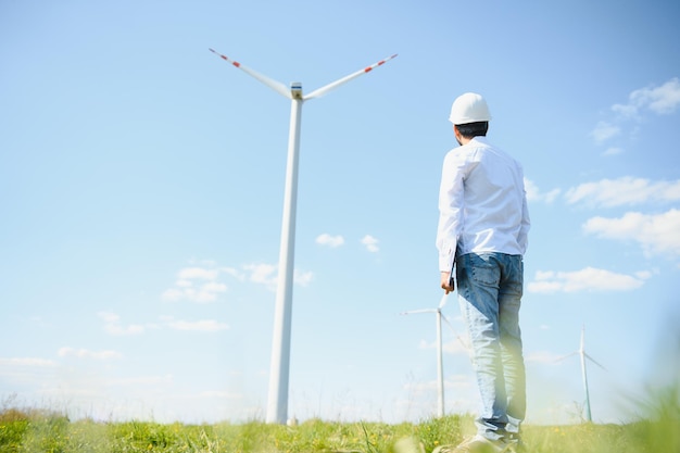 Engineer India man working at windmill farm Generating electricity clean energy Wind turbine farm generator by alternative green energy Asian engineer checking control electric power