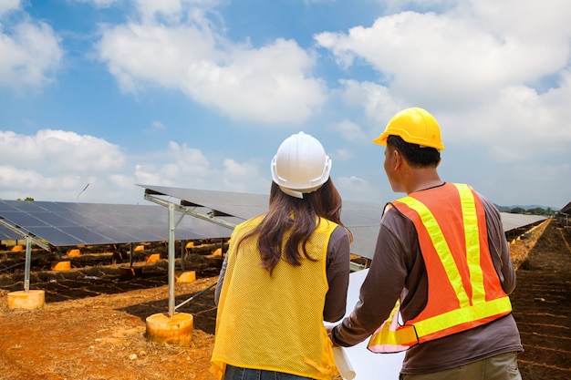 Foto ispettore ingegnere maschio e femmina che lavorano nella fattoria elettrica del pannello solare. concetto di energia verde del parco di celle fotovoltaiche