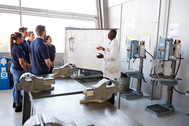 Engineer instructing apprentices at a whiteboard side view