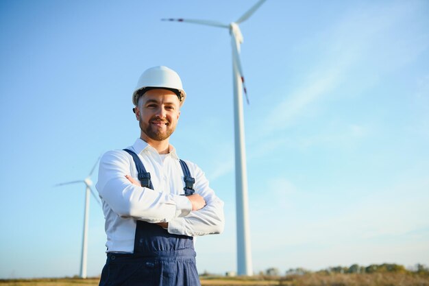 Engineer is checking energy production on wind turbine. Worker in windmills park in helmet.