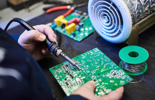 Engineer is soldering a computer board circuit chip or microchip Repairing Hardware Equipment Repair Shop and Worker with Tools Testing Modern Digital Device on Desk Electronic Devices Concept