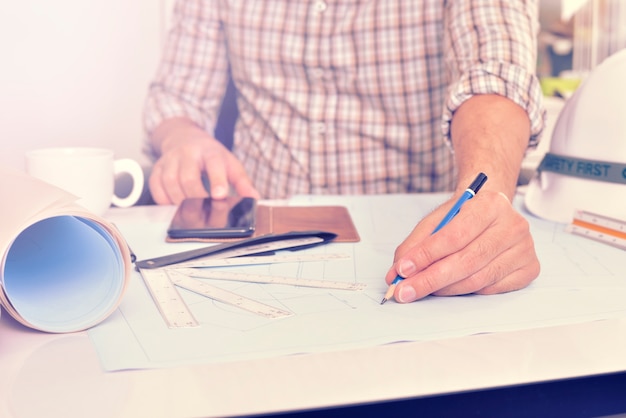 Engineer is working on the desk with drawing plan