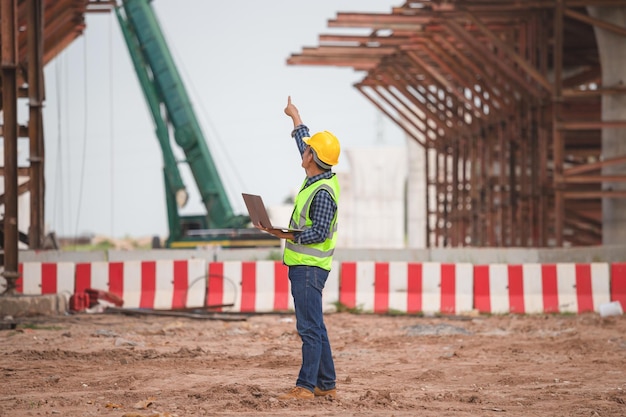 Foto ingegnere con laptop che controlla il cantiere infrastrutturale capo operaio sul cantiere