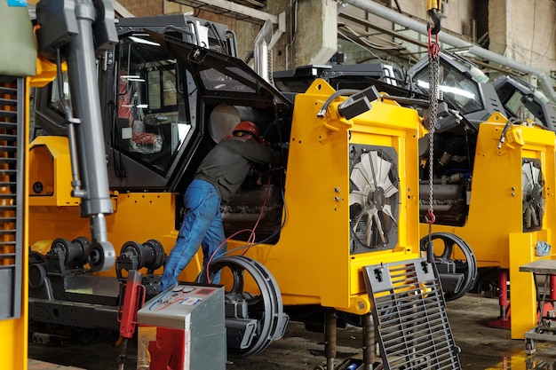 Engineer of modern industrial or construction plant examining motor of machine