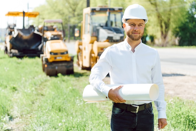 Engineer near road machinery. The concept of building a new asphalt road. Road repair. Road service worker near the rink.