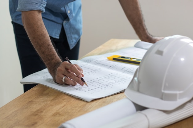 Ingegnere che progetta sulla stampa blu sul tavolo di lavoro