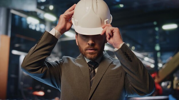 Engineer putting protective helmet smiling camera at modern factory closeup