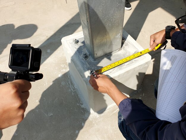 Photo engineer rechecking distance of base plate connection bolts for steel structure of solar carport