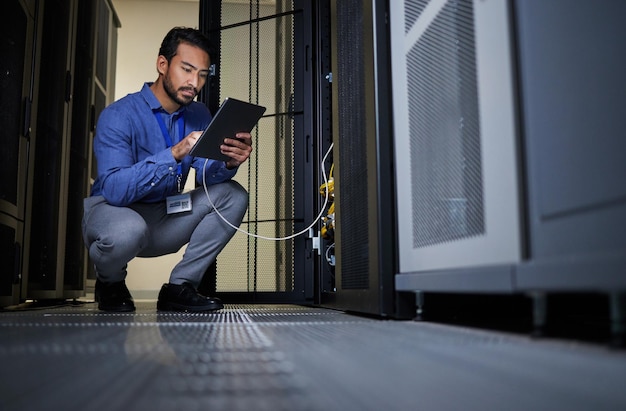 engineer server room and man with tablet for database connection cable maintenance or software update at night cybersecurity wire it and male coder with technology for networking in data center