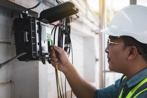 Engineer or technician checking fiber optic cables in internet\
splitter box.fiber to the home equipment. ftth internet fiber\
optics cables and cabinet.