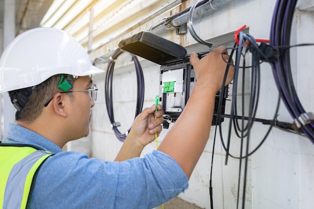 Engineer or technician checking fiber optic cables in internet splitter box.Fiber to the home equipment. FTTH internet fiber optics cables and cabinet.