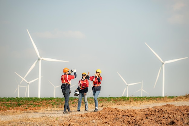 Engineer and technician greet each other in wind turbine farm with blue sky background