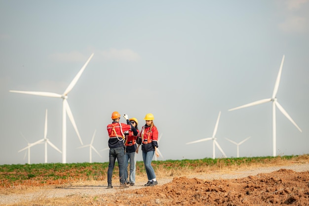 Engineer and technician greet each other in wind turbine farm with blue sky background