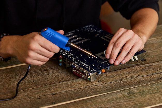 Engineer or technician repair electronic circuit board with soldering iron.