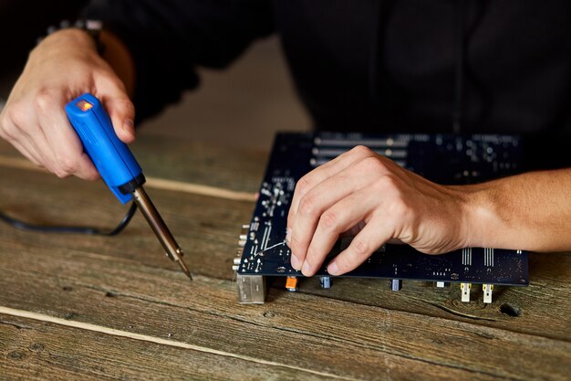 Инженер или техник ремонтируют электронную плату с паяльником.