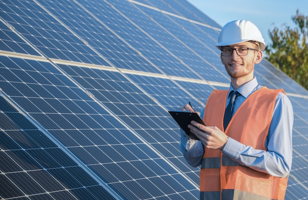 Engineer in uniform standing on a background of solar panels.the solar farm check the operation of the system, alternative energy to conserve the world's energy, photovoltaic module idea for clean