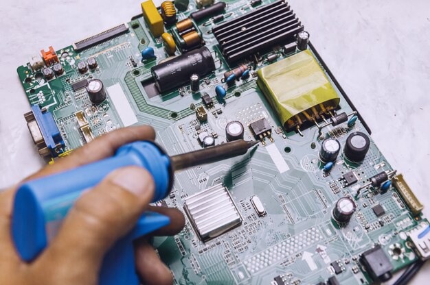 Photo engineer use soldering iron to repair television board