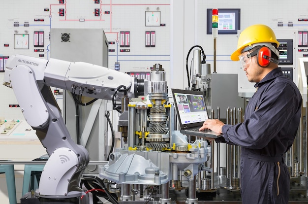 engineer using laptop computer for maintenance automatic robotic hand machine tool in automotive industry