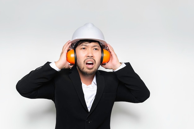 Engineer wearing protective helmet and soundproofing on white background