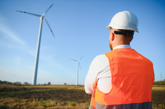 Engineer in wheat field checking on turbine production