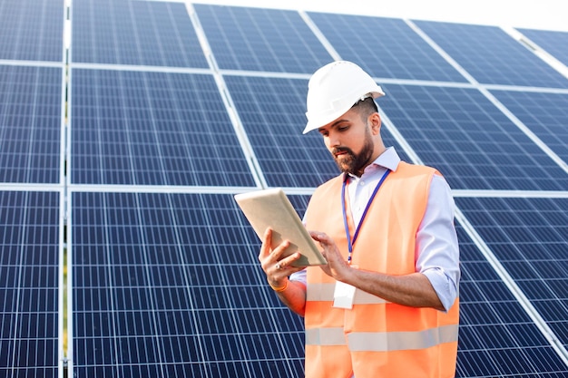 Engineer with a tablet stands on the background of a solar station